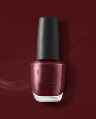 OPI Vampire State Building nail lacquer bottle displays a deep burgundy red fall nail color with a black cap, set against a glossy matching red polish background.