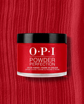 OPI Powder Perfection Vodka & Caviar dipping powder jar in rich red with a black lid, centered on a textured red nail color swatch for bold fall nail colors.