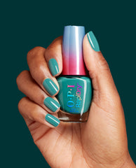 Hand with teal manicured nails holds OPI RapiDry What a Winterful World nail polish bottle with ombré blue-to-pink cap against a deep green background, showcasing a single-shade OPI nail polish gift set for fast-drying winter nail looks.