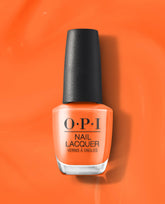 OPI Your Zestination Awaits nail lacquer bottle in bright orange-coral polish stands upright with a black cap against a glossy orange background.