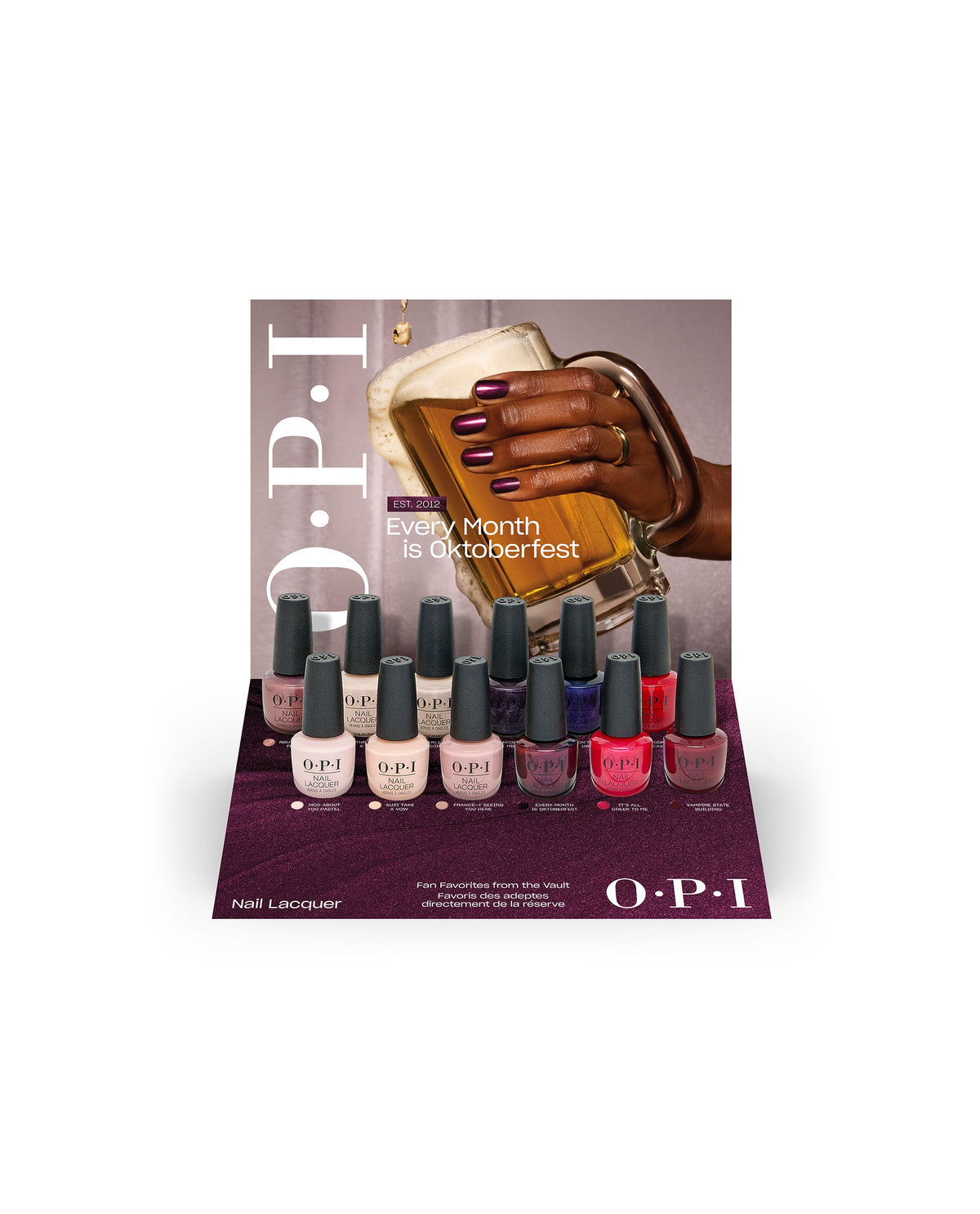 OPI Fall ’26 Nail Lacquer 12PC Vac Tray Display showcases 12 fall nail colors in a burgundy retail tray with an Oktoberfest-themed backdrop, featuring nude, pink, plum, red, and berry shades.