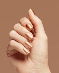 Hand showing short, neatly manicured nails painted in 2000 Karats Infinite Shine, a metallic rose-gold OPI nail polish, catching light against a warm tan background to highlight the glossy, high-shine salon finish.