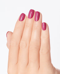 Hand with neatly manicured nails painted in 7th & Flower nail lacquer, a glossy medium-berry shade similar to OPI nail polish, shown against a clean white background to highlight the smooth, even color coverage.