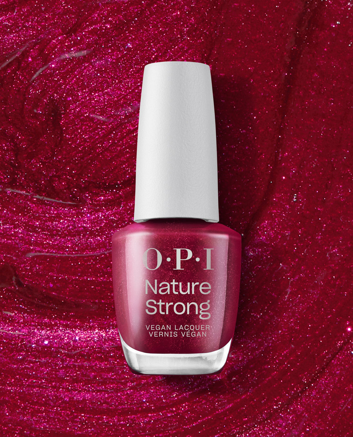 OPI Nature Strong Vegan Nail Lacquer in Raisin Your Voice stands against a sparkling berry-red polish background, showcasing a deep raisin shimmer shade for fall nail colors.