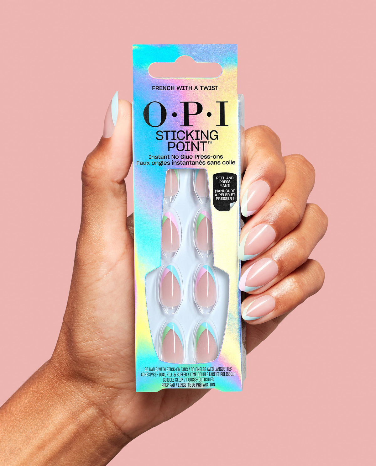 Hand holds OPI Sticking Point French With a Twist no-glue press-on nails in iridescent packaging, with pastel French tip manicure displayed against a pink background.