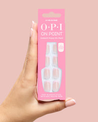 OPI On Point La Vie en Rosé instant press-on mani box held in a hand, showing glossy nude-pink French tip nails in bright pink packaging against a soft pink background.