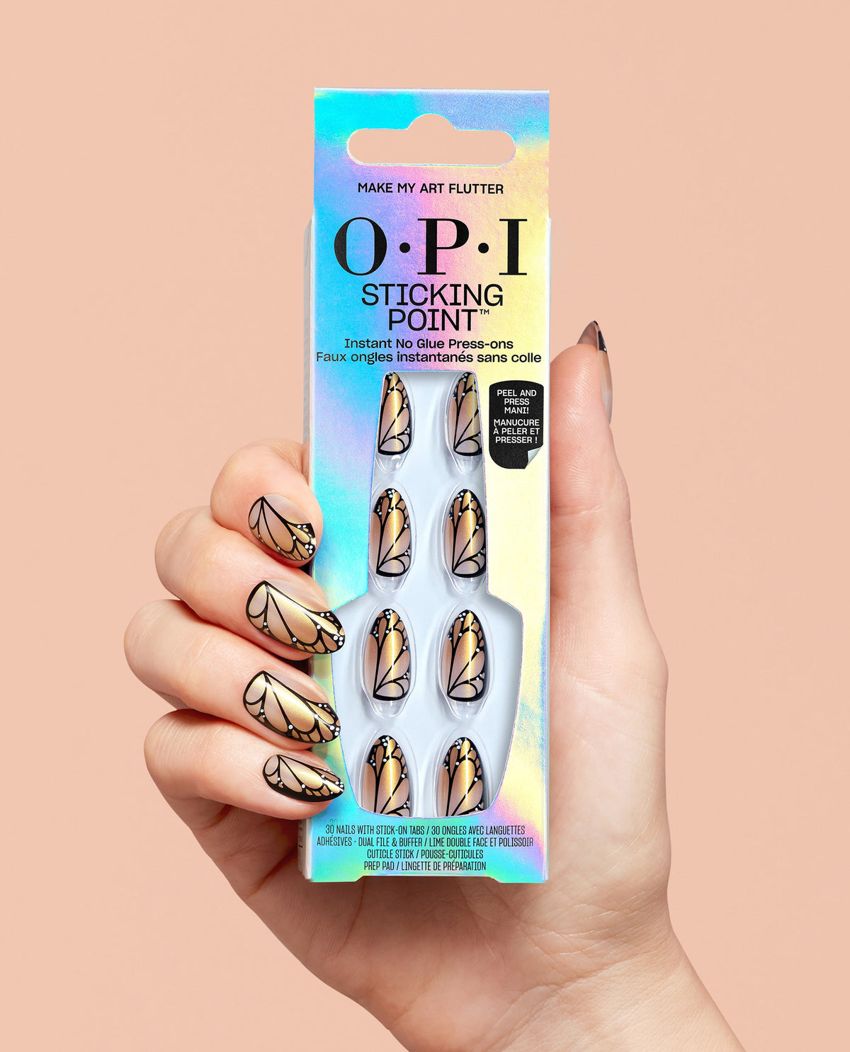 Hand with gold, black, and nude butterfly-wing press-on nails holds OPI Sticking Point Make My Art Flutter instant no-glue press-ons in iridescent packaging, a bold pick for fall nail colors.