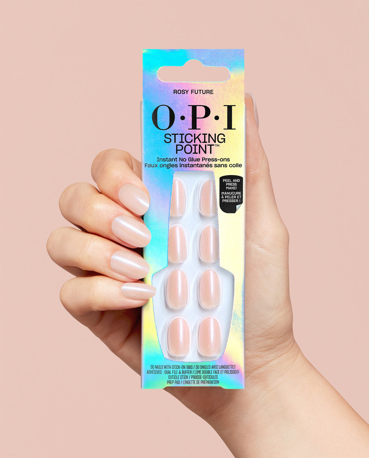 Hand holds OPI Sticking Point Rosy Future trending press-on nails in iridescent packaging, showing pearly pale pink artificial nails on a blush pink background.