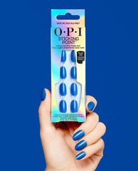 Hand wearing blue shimmer nails holds OPI Sticking Point Send Me Into Glo-Rbit no-glue press-on nails in iridescent packaging against a bold blue background.