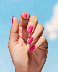 Hand shows glossy hot pink nails painted with A Kick in the Bud, OPI Nature Strong Vegan Nail Lacquer, fingers fanned against a sunny blue sky, a vibrant shade ideal for spring nail colors and current spring nail trends.