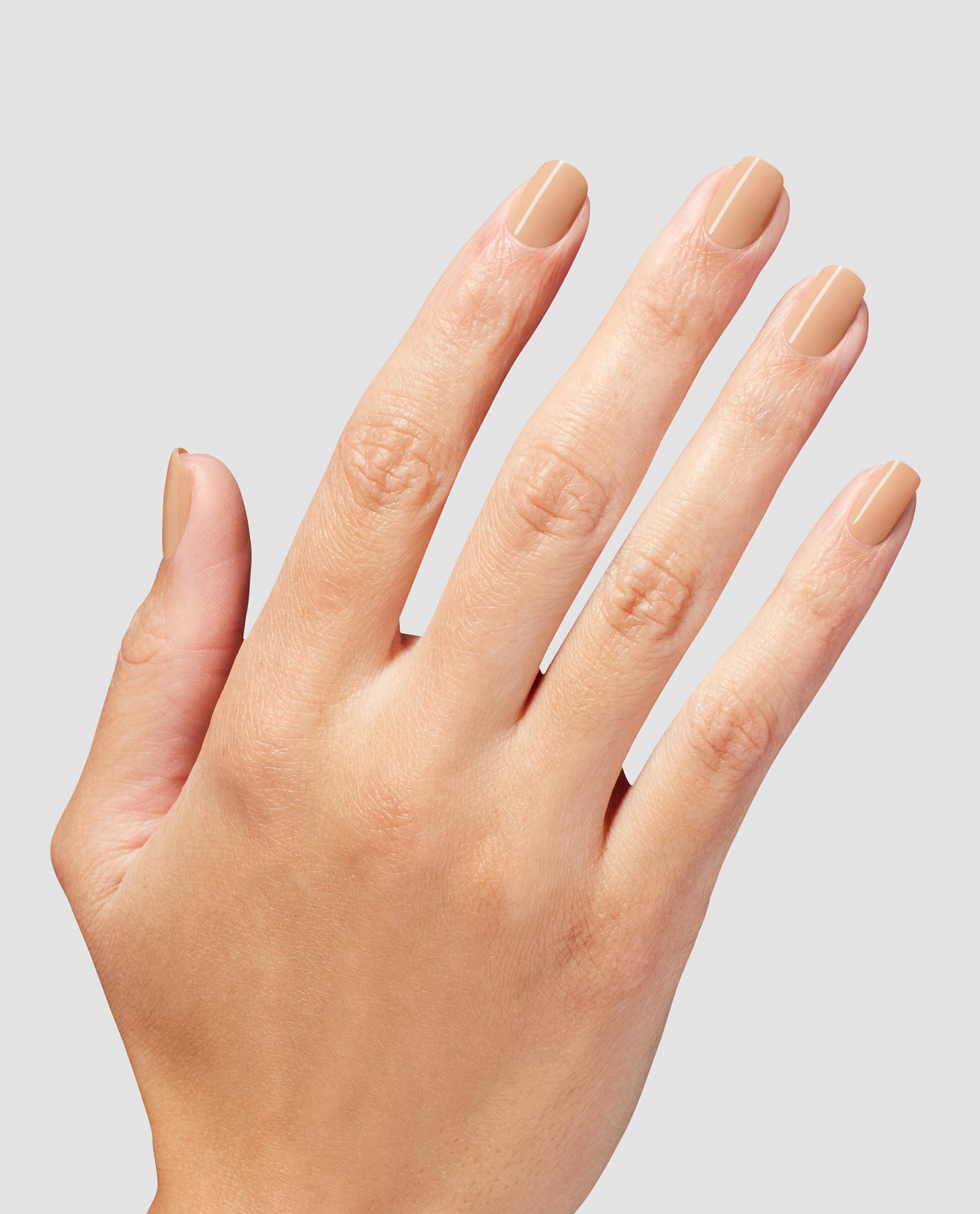 Hand with neatly manicured nails painted in A Total Suzi Infinite Shine, a glossy beige nude OPI nail polish, shown against a light gray background to highlight the smooth, even coverage and natural everyday shade.
