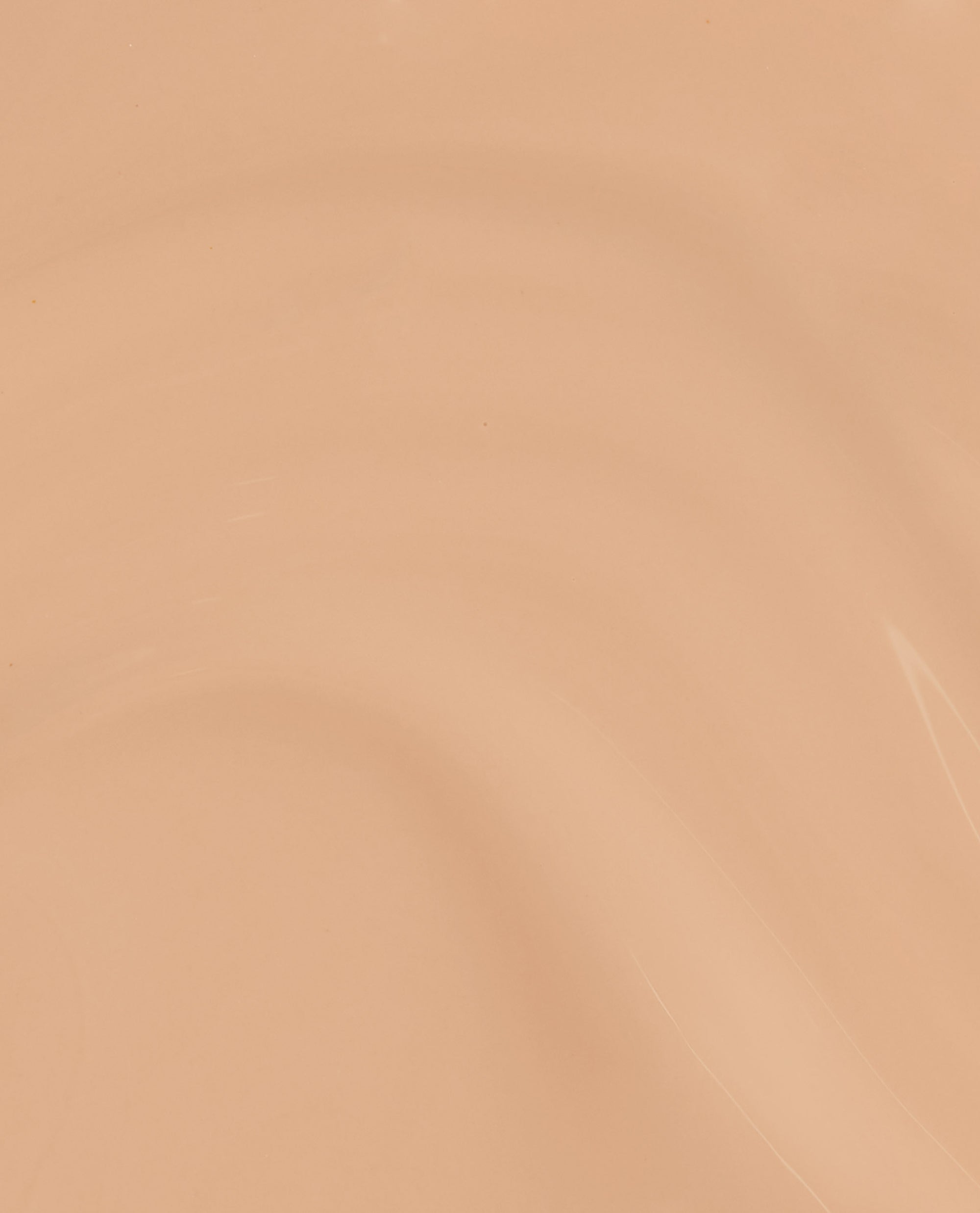A smooth, glossy swatch of OPI nail polish in A Total Suzi Infinite Shine, showing a warm peachy beige nude shade with subtle light reflections across the creamy lacquer surface.