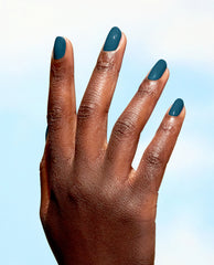Manicured hand flaunts glossy deep green nails painted with OPI Nature Strong Vegan Nail Lacquer, All Heal Queen Mother Earth, against a soft sky-blue background—a chic green nail polish pick for spring nail colors.