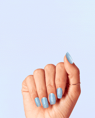 Hand with medium-length nails painted in Angels Flight to Starry Nights, a shimmering sky-blue OPI nail polish nail lacquer, held against a soft light blue background to showcase the glittery, iridescent finish.