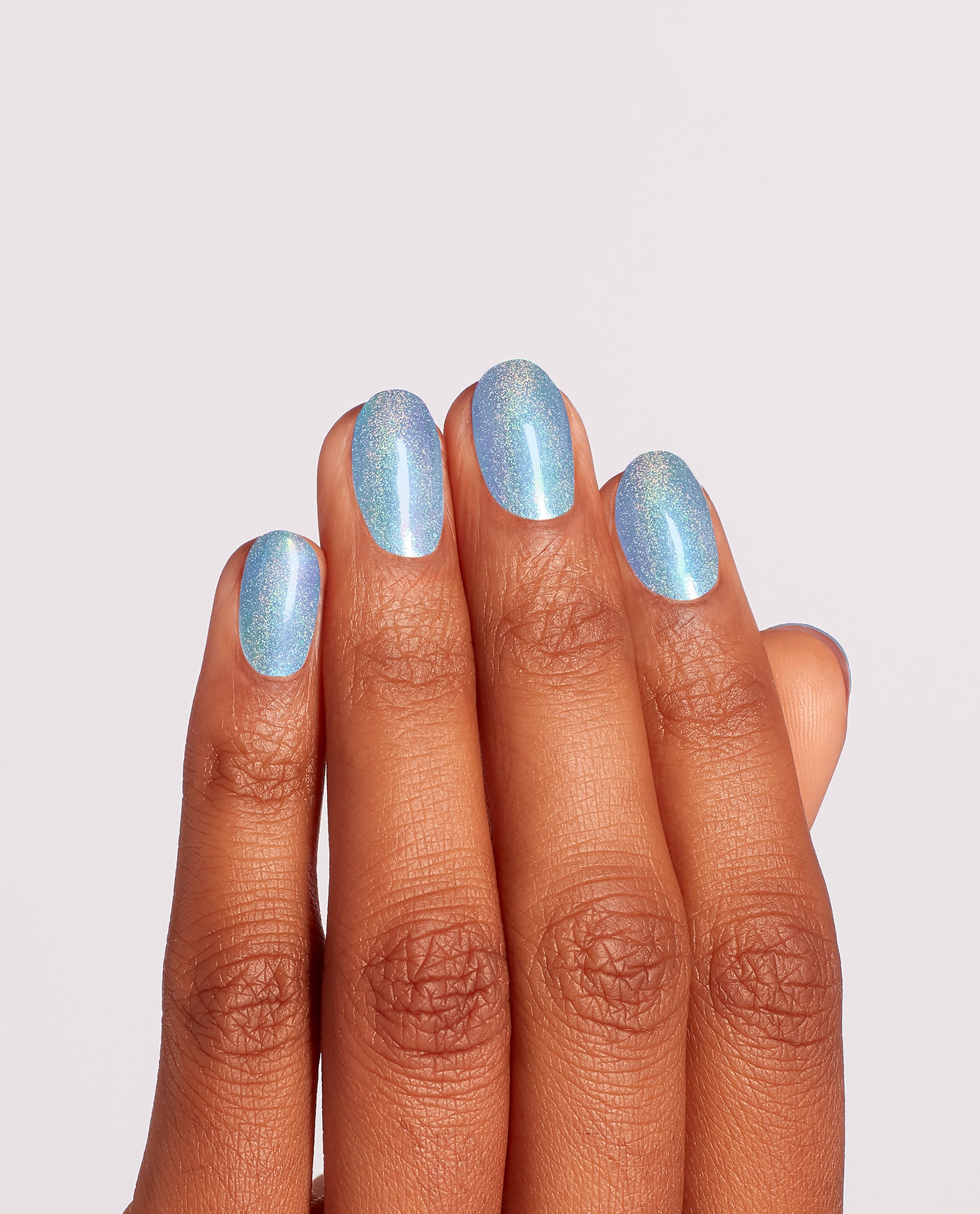 Hand with neatly manicured oval nails wearing Angels Flight to Starry Nights OPI nail polish, a shimmering sky blue holographic nail lacquer, shown in close-up against a clean light background for a glossy salon-quality finish.