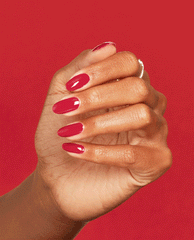 Hand with medium skin tone flexing fingers to showcase glossy crimson nails painted with Art Walk in Suzi's Shoes OPI nail polish nail lacquer against a bold red background, highlighting the smooth, even salon-quality manicure finish.