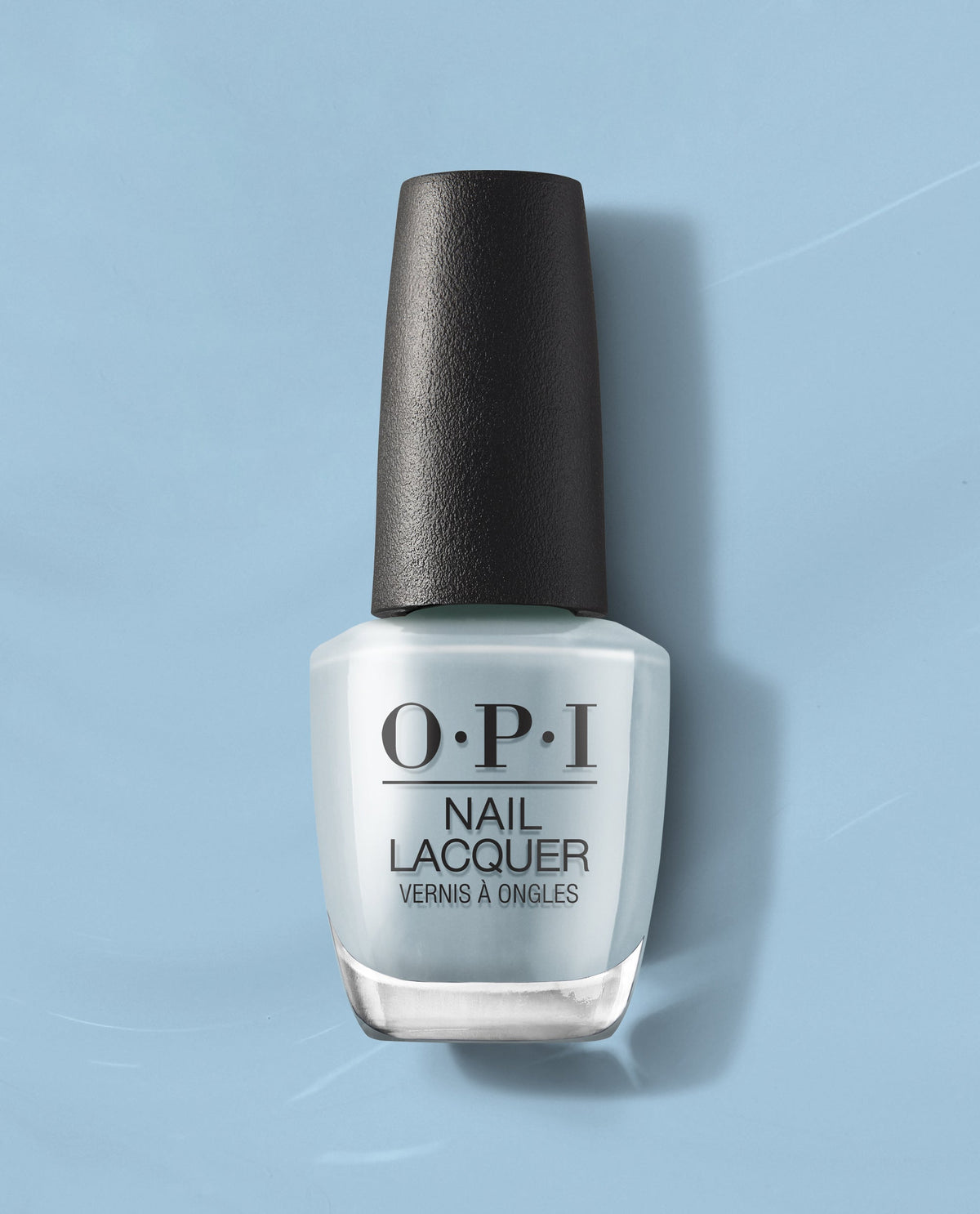 OPI Baggy Jean Baby nail lacquer stands upright, displaying a soft denim-blue creme polish on a matching blue studio backdrop, a chic addition to fall nail colors for US manicures.