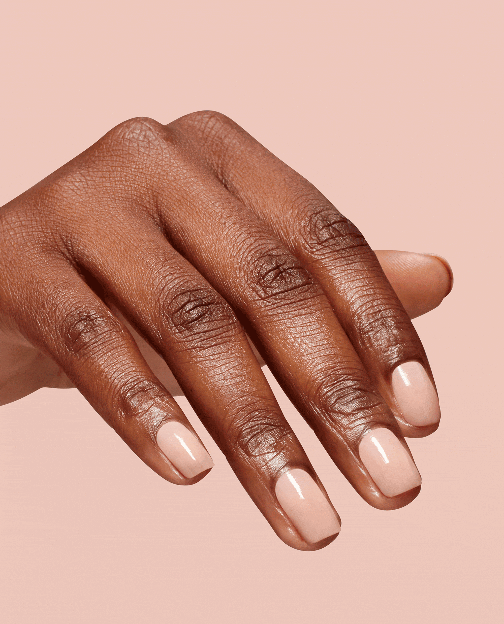 Hand with neatly manicured nails showcases OPI Bubble Bath Infinite Shine, a soft pink nude polish with a glossy finish, against a matching blush background, highlighting this elegant nail polish gift set for everyday wear.