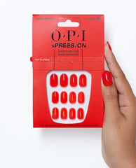 OPI xPRESS/ON Cajun Shrimp press-on nails in glossy coral red are shown in red packaging, held by a hand wearing the trending shade against a clean white background.