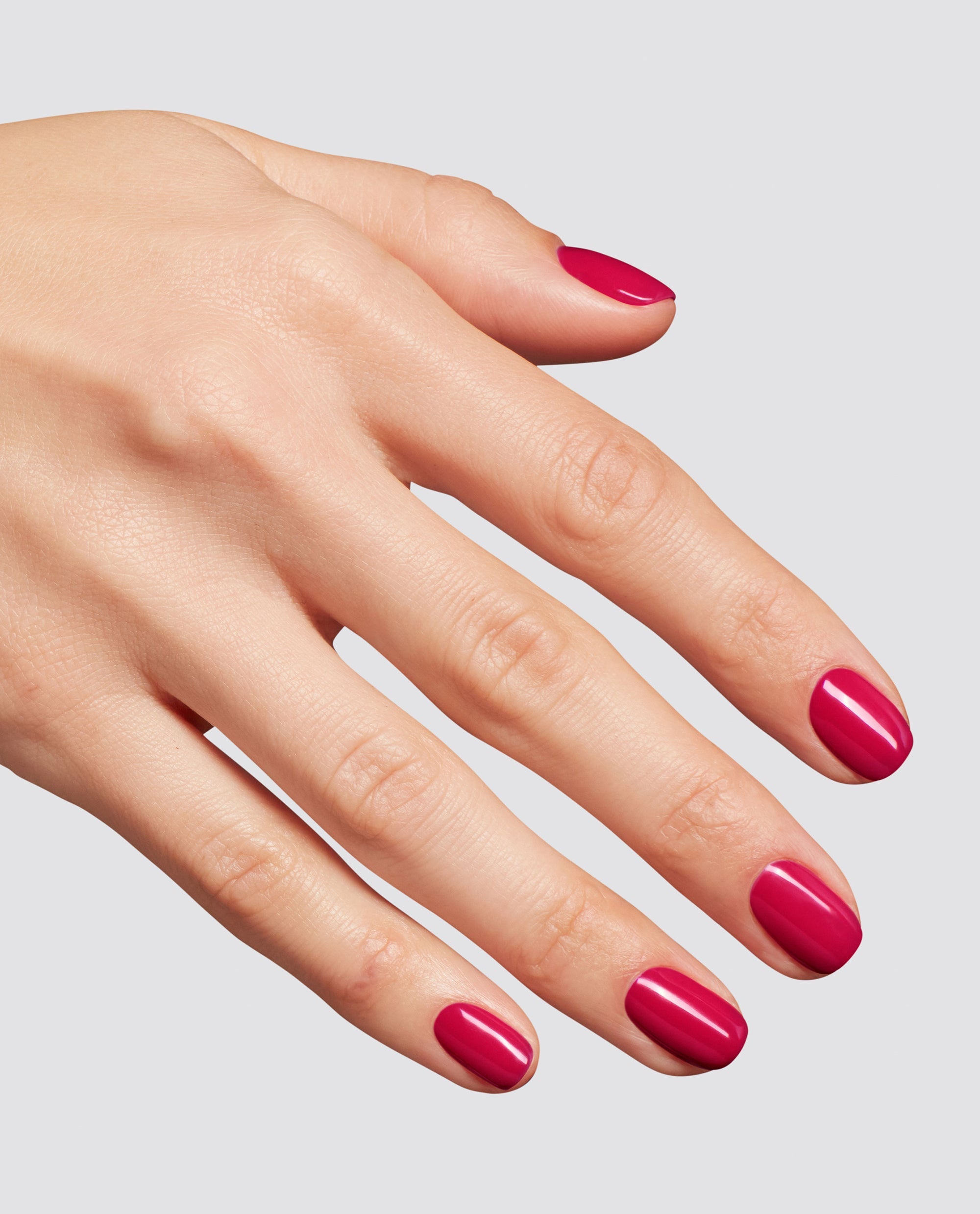 Hand with neatly manicured nails painted in a glossy bright berry pink shade, showcasing the Clawberry Margarita at-home gel nail polish, ideal as an OPI-inspired nail polish gift set option, against a clean light gray background.