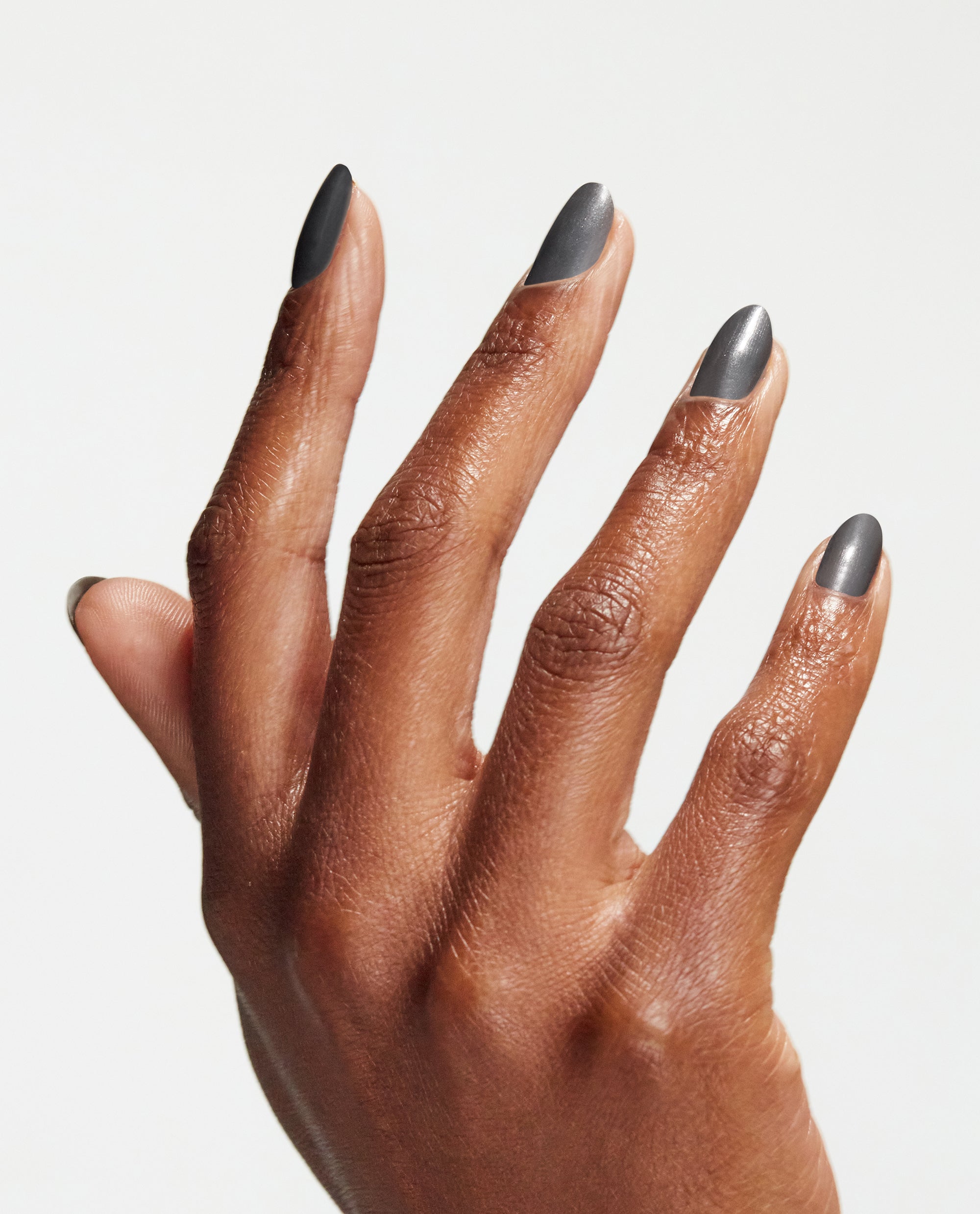 Hand with long, almond-shaped nails painted in Clean Slate gray nail lacquer, showcasing a smooth, satin finish similar to OPI nail polish against a bright white background.