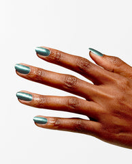 Hand displays metallic teal green nail polish, OPI Infinite Shine Cos-mo Money, with a glossy shimmer on neatly filed nails, showcasing spring nail colors against a clean white background.