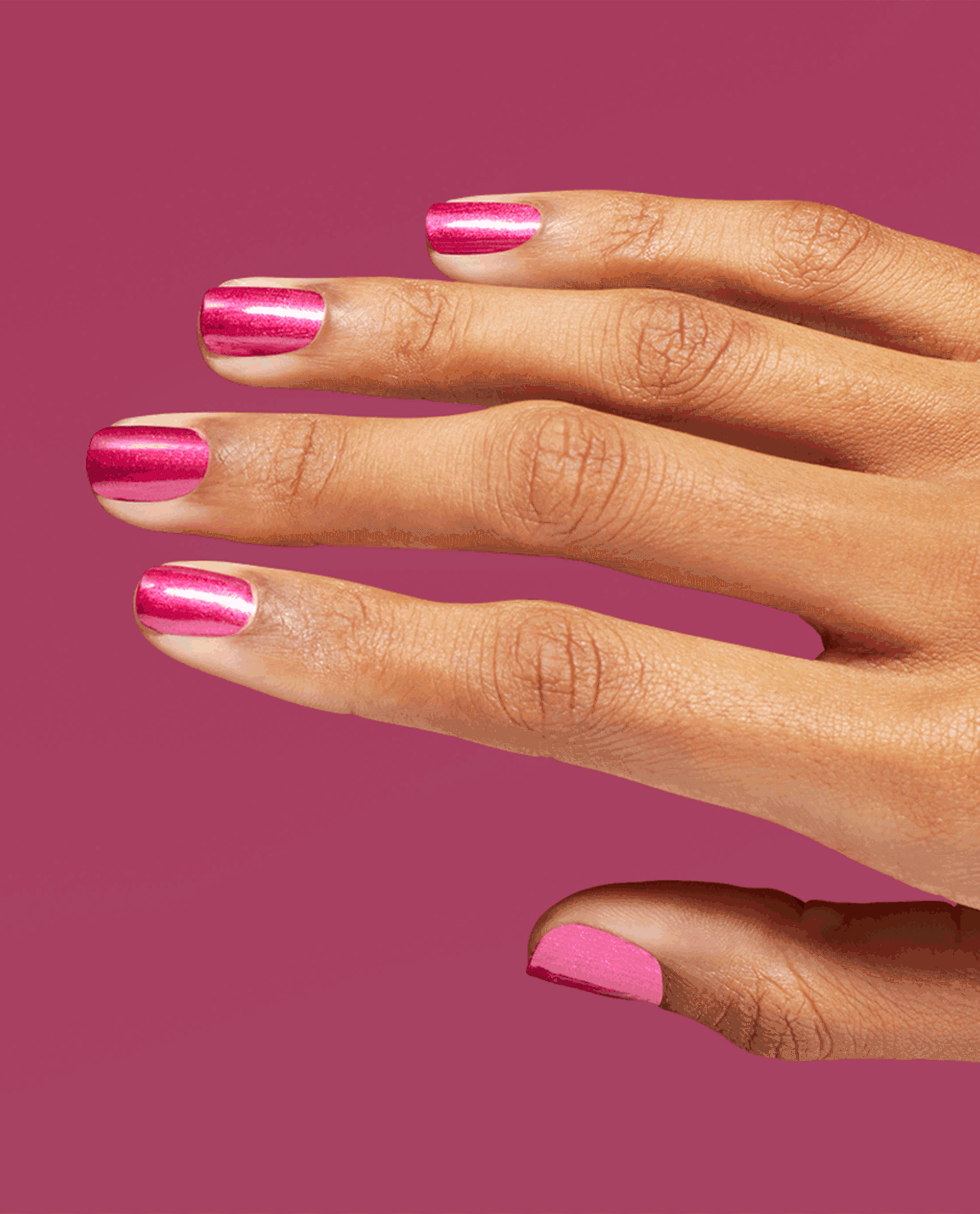 Hand with short nails painted in OPI nail polish DeJa RoUgE Infinite Shine, showing a bright metallic fuchsia pink manicure against a matching magenta background for a bold, glossy look.