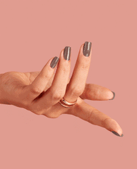 Hand modeling glossy taupe-brown OPI Espresso Your Inner Self nail lacquer, a chic fall nail color, with long squared nails and a gold ring against a soft pink background.