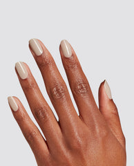 Hand displays glossy almond nails painted with OPI Espresso Martini Please at-home gel nail polish, a creamy beige neutral for fall nail colors, against a light gray background.