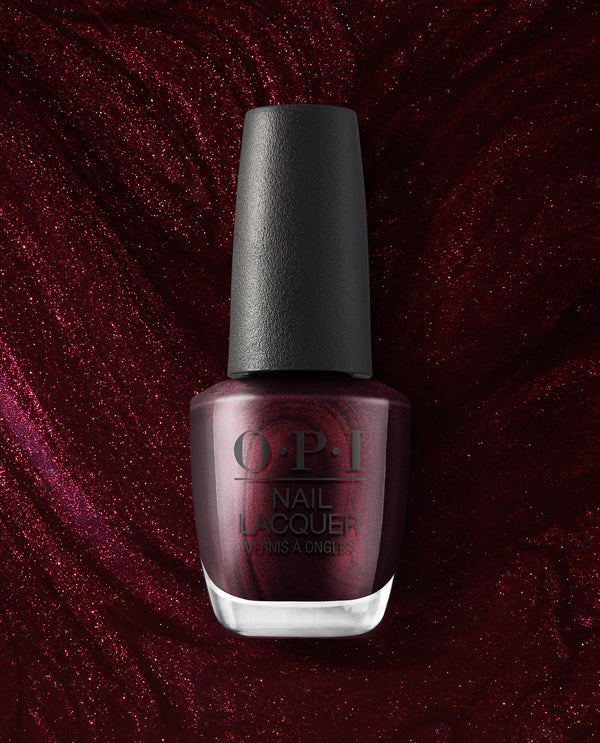 OPI Every Month is Oktoberfest nail lacquer bottle stands against a shimmering burgundy background, showcasing a deep wine-red metallic shade for fall nail colors.