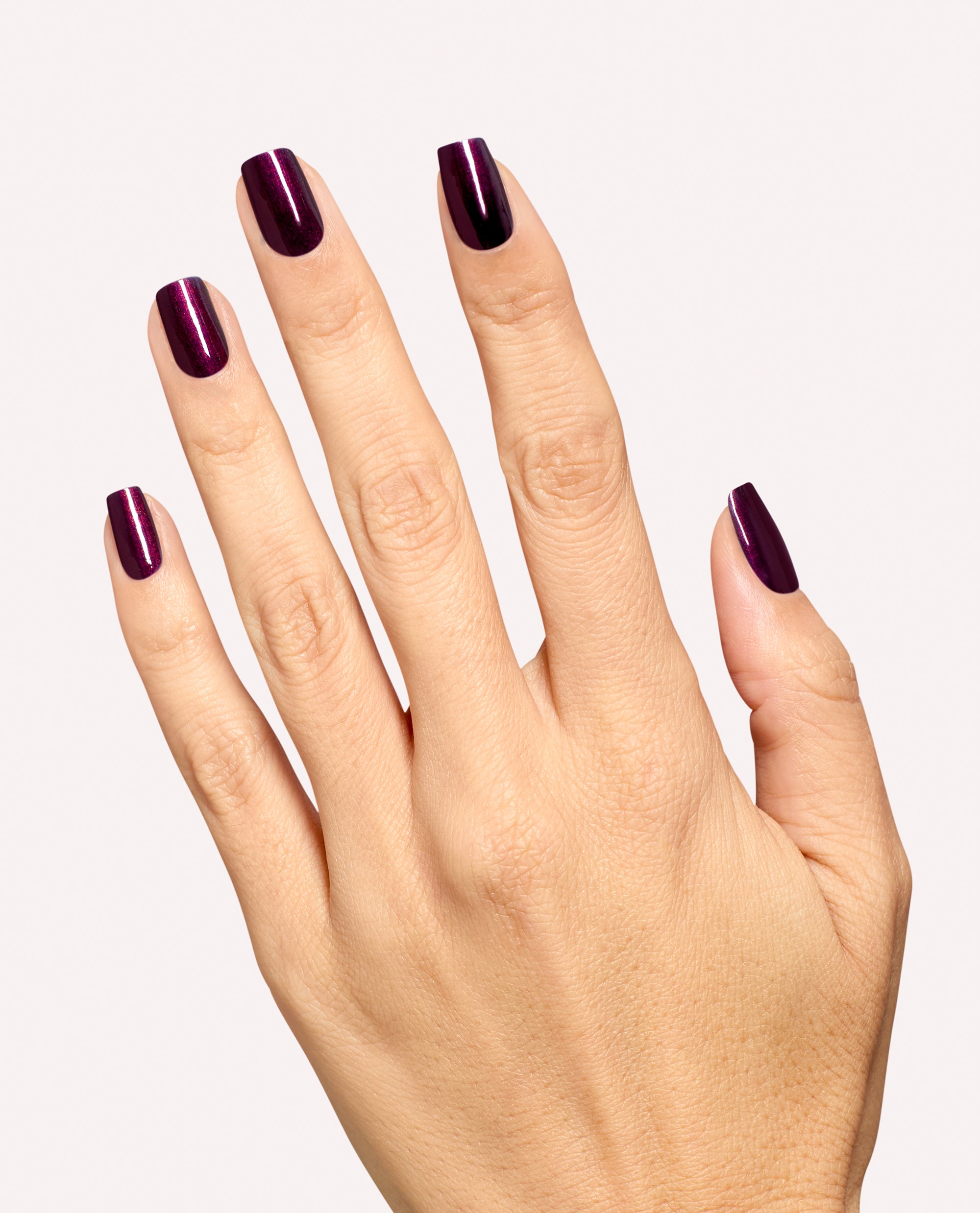 Hand modeling glossy deep plum burgundy nails using Every Month is Oktoberfest dipping powder by OPI, a rich shade for fall nail colors on a clean white background.