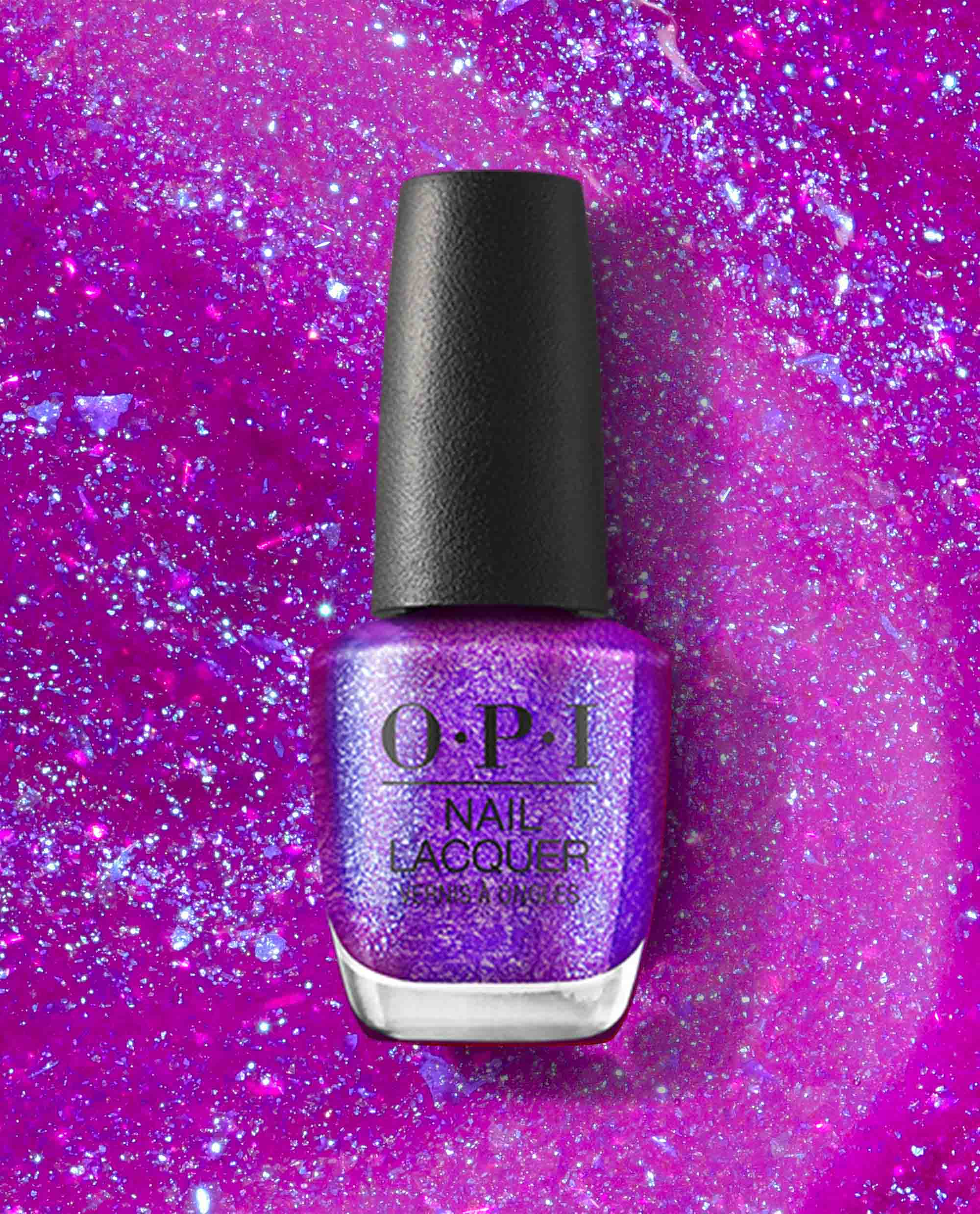 OPI nail polish bottle of Feelin’ Libra-ted Nail Lacquer standing upright, displaying a shimmering purple glitter shade against a vibrant pink and violet sparkling background, highlighting the bold, cosmic-inspired color for manicures.