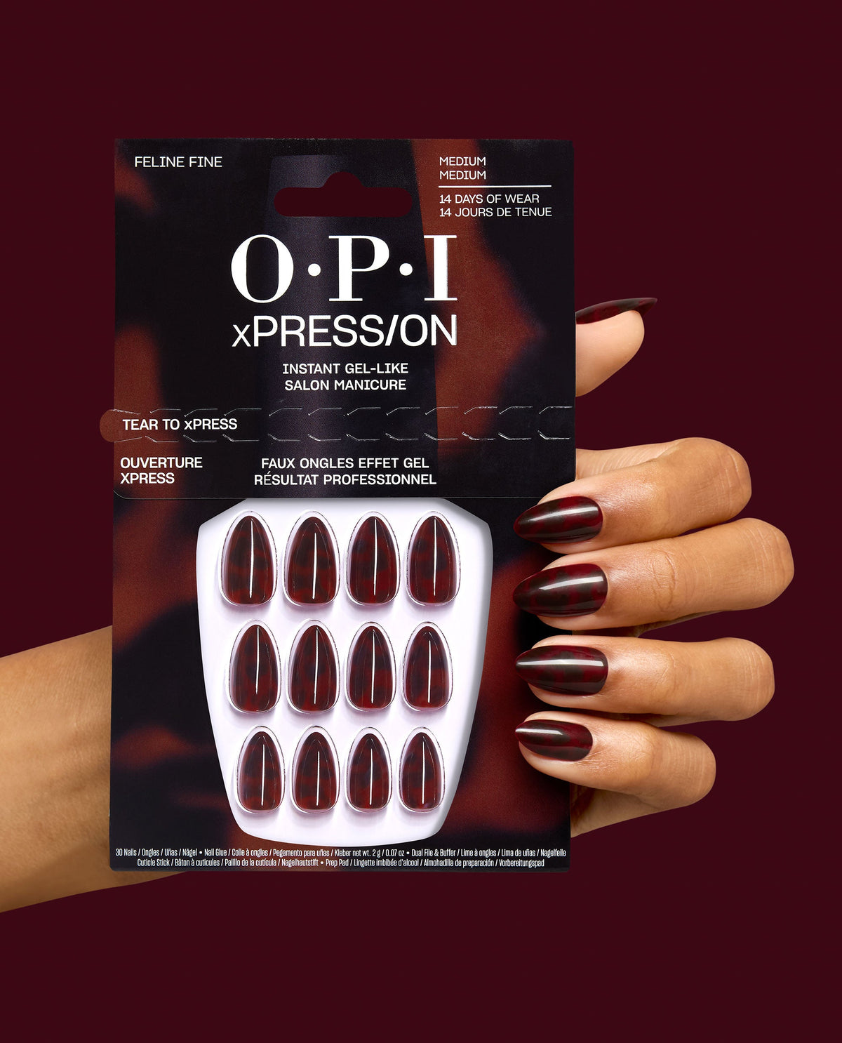 OPI xPRESS/ON Feline Fine press-on nails held by a manicured hand, showing medium almond gel-like nails in deep burgundy-black tortoiseshell, a dramatic option for fall nail colors.