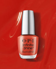 OPI Infinite Shine Full of Glambition coral-orange gel-like lacquer bottle standing on a glossy red polish background, a vibrant pick for fall nail colors.