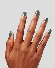 Hand displays short nails painted in OPI nail polish Get in Platform-ation Infinite Shine, a glossy deep gray shade, against a light gray background, showcasing smooth, full-coverage color on every fingernail.