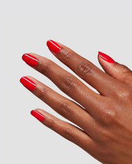 Glossy Goddess at-home gel nail polish creates a vivid glossy red manicure on almond-shaped nails, an OPI fall nail colors-inspired look on a hand against a light gray background.