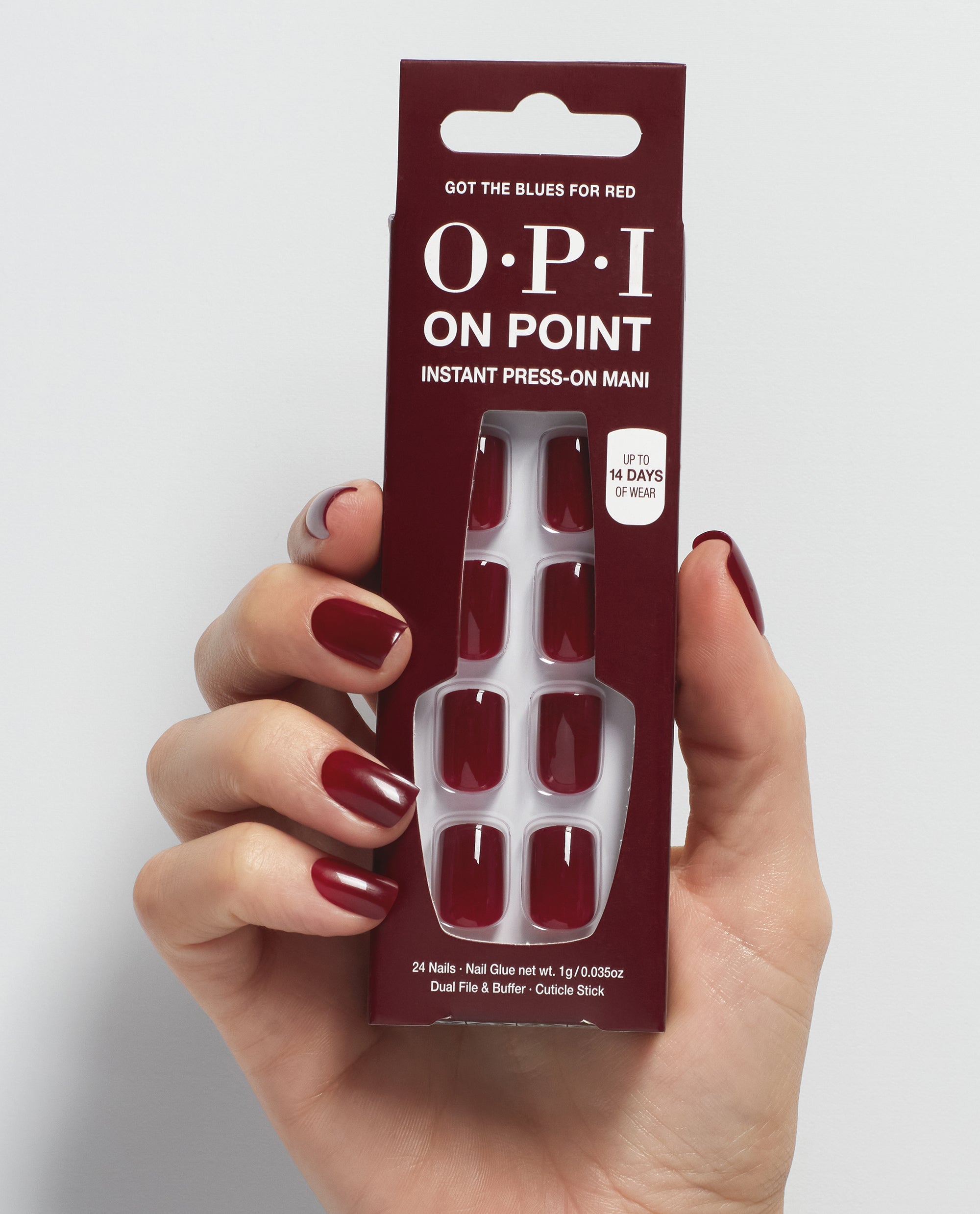Hand with glossy deep burgundy nails holds OPI On Point Got the Blues for Red instant press-on mani, a rich red shade among classic fall nail colors.