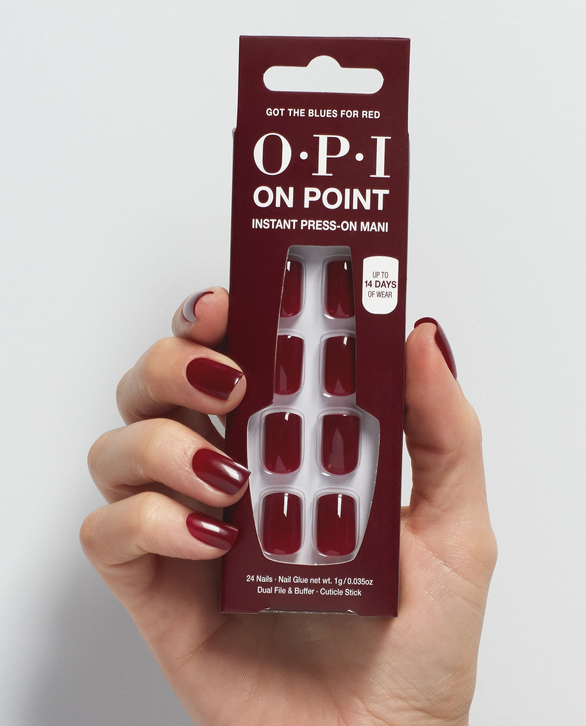 Hand with glossy deep burgundy nails holds OPI On Point Got the Blues for Red instant press-on mani, a rich red shade among classic fall nail colors.