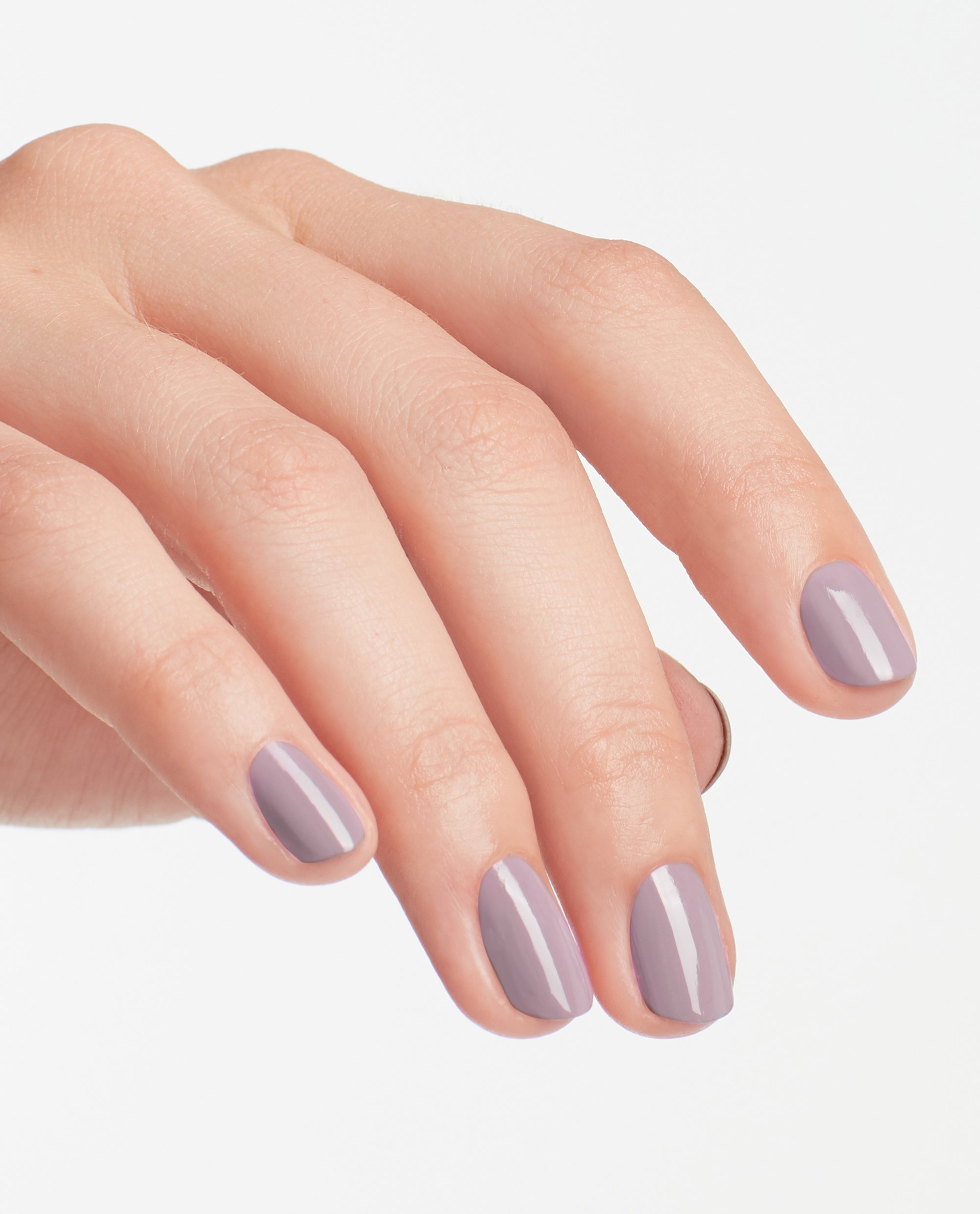 Hand showing short, neatly manicured nails painted in OPI nail polish Graffiti Sweetie, a glossy muted lavender nail lacquer, against a clean white background to highlight the soft pastel color and smooth finish.