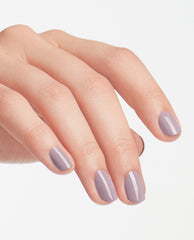 Hand showing short, neatly manicured nails painted in OPI nail polish Graffiti Sweetie, a glossy muted lavender nail lacquer, against a clean white background to highlight the soft pastel color and smooth finish.