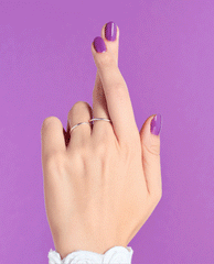 Hand with fingers crossed shows glossy purple nails painted with Grandma Kissed a Gaucho nail lacquer, highlighting the vibrant OPI nail polish shade against a matching lavender background.