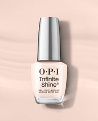 OPI Infinite Shine I’m the Bossa Nova Now gel-like lacquer bottle in a soft pale peach nude shade, shown upright on a blush background for fall nail colors.