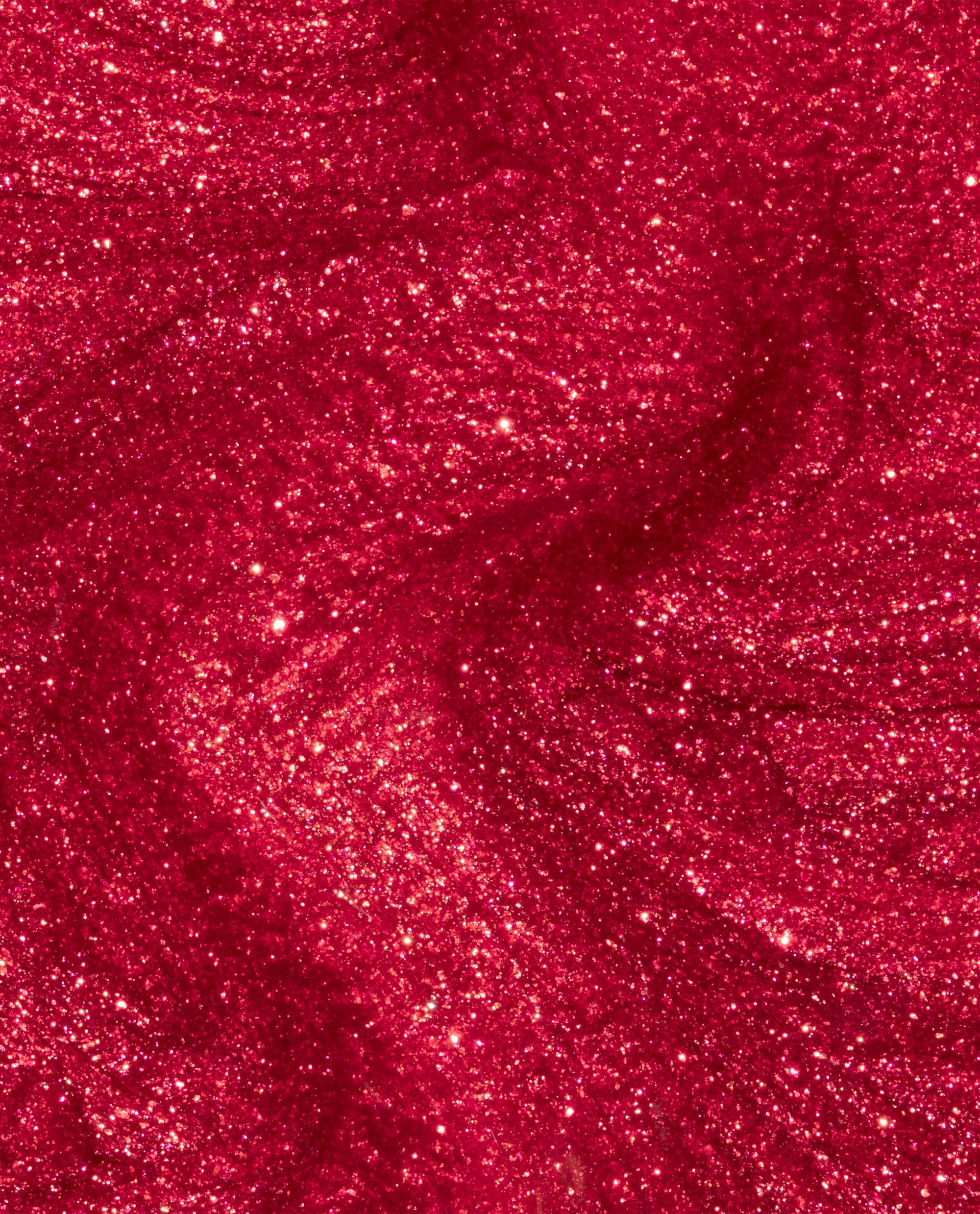 Kiss My Aries nail lacquer swirls in a close-up, showing rich ruby-red OPI nail polish with dense golden shimmer and glittery metallic finish, highlighting its bold, sparkly texture for vibrant manicures.