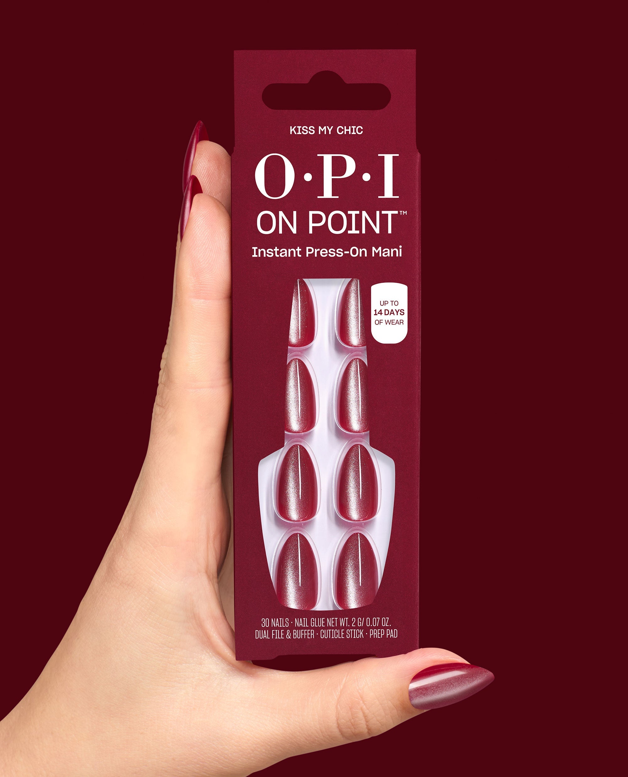 OPI On Point Kiss My Chic instant press-on manicure box is held in a manicured hand, showing shimmery burgundy fall nail colors and up to 14 days of wear on a deep red background.