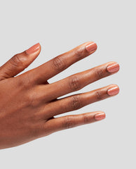 Hand with neatly manicured nails wearing OPI nail polish Knee High Stock-blings Infinite Shine in a shimmery rose-peach shade, fingers slightly spread against a light gray background, showing glossy, even coverage and sparkle.