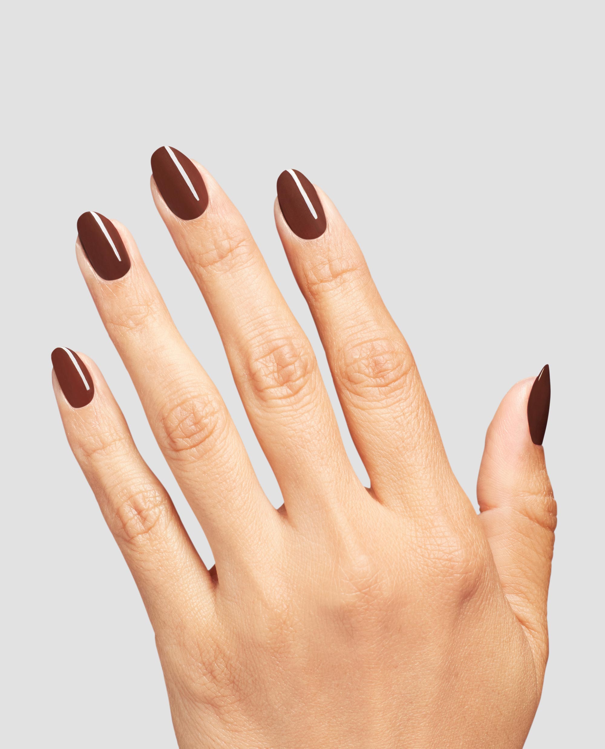 Hand modeling OPI Infinite Shine Lip Hot Liner, a glossy deep reddish-brown manicure with rounded nails, showcasing rich fall nail colors on a light gray background.