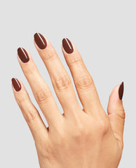 Hand modeling OPI Infinite Shine Lip Hot Liner, a glossy deep reddish-brown manicure with rounded nails, showcasing rich fall nail colors on a light gray background.