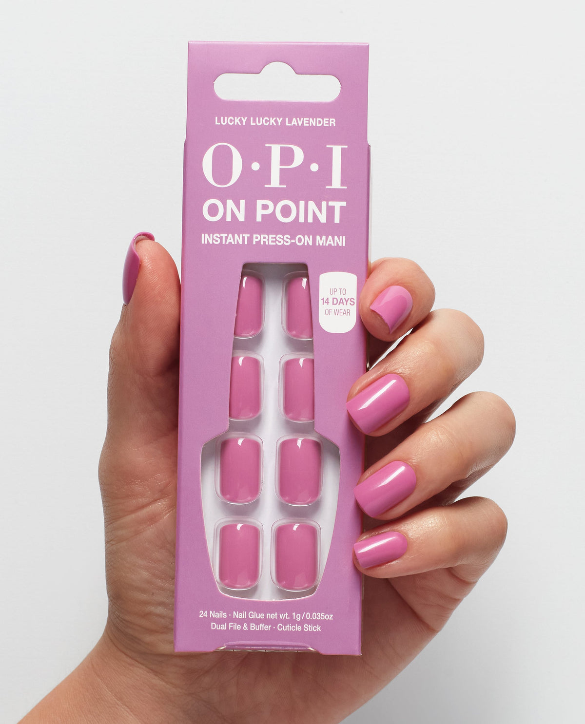A manicured hand wearing glossy Lucky Lucky Lavender OPI On Point press-on nails holds the matching pack, highlighting a soft lavender-pink option among OPI fall nail colors on a white background.