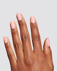 Hand modeling glossy pale pink Made Ya Blush at-home gel nail polish on short rounded nails, a trending OPI manicure shade against a clean light gray background.