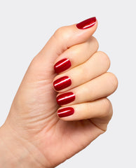 Hand modeling OPI Infinite Shine Malaga Wine Not?, a glossy deep red shimmer manicure ideal for fall nail colors, shown on short rounded nails against a light gray background.